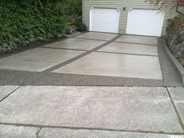 A concrete driveway leading to a garage with two white garage doors