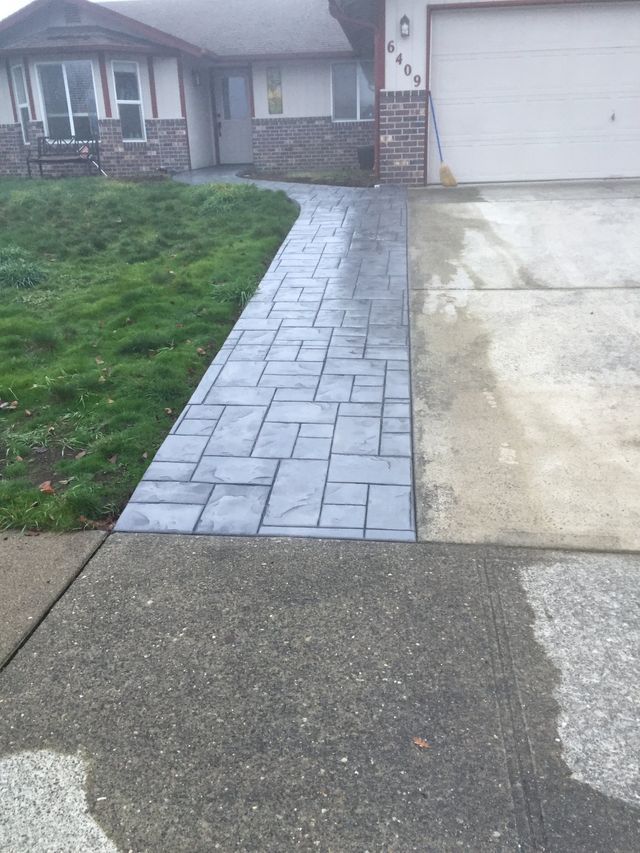 A concrete walkway leading to a house with a garage