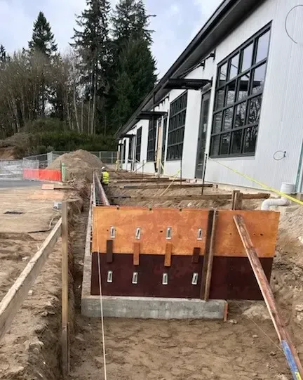Concrete walkway and retaining walls under construction next to a house. Rebar visible.