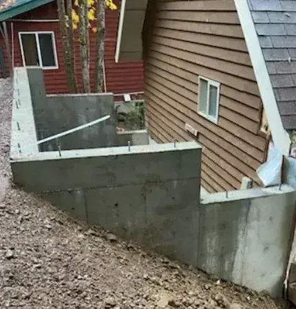 A concrete wall is being built in front of a house.