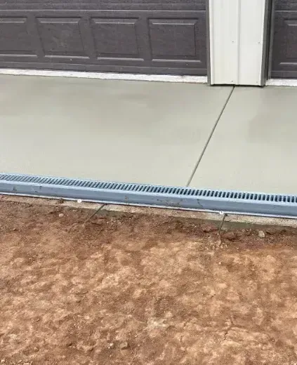 A concrete walkway is being built next to a garage door.