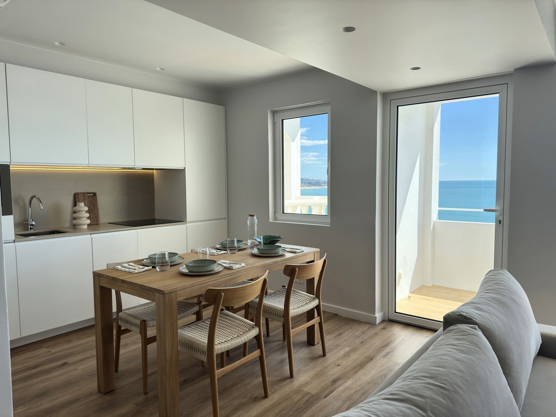 Uma sala de estar com mesa e cadeiras e vista para o mar