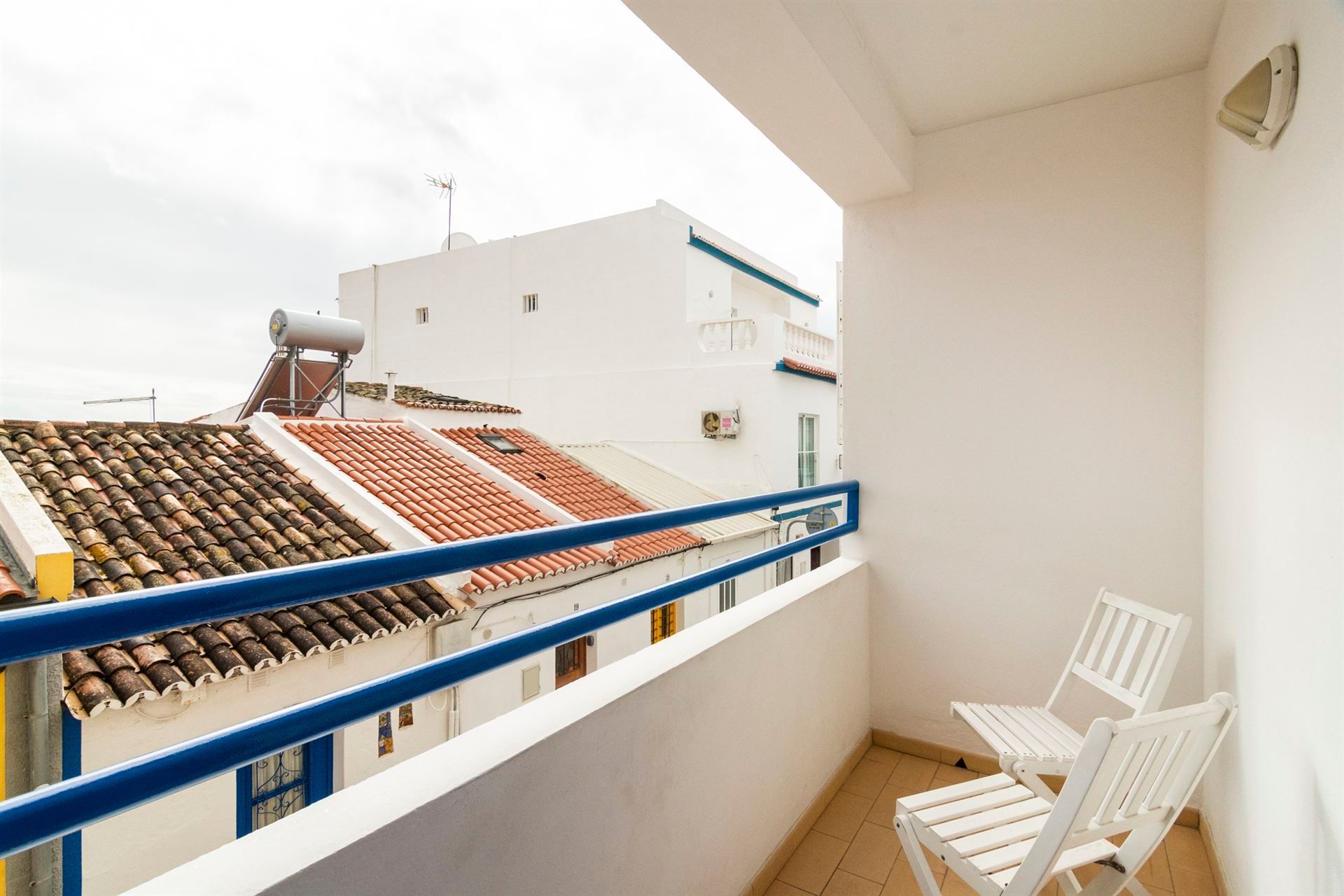 Uma varanda com duas cadeiras e uma mesa com vista para um prédio.