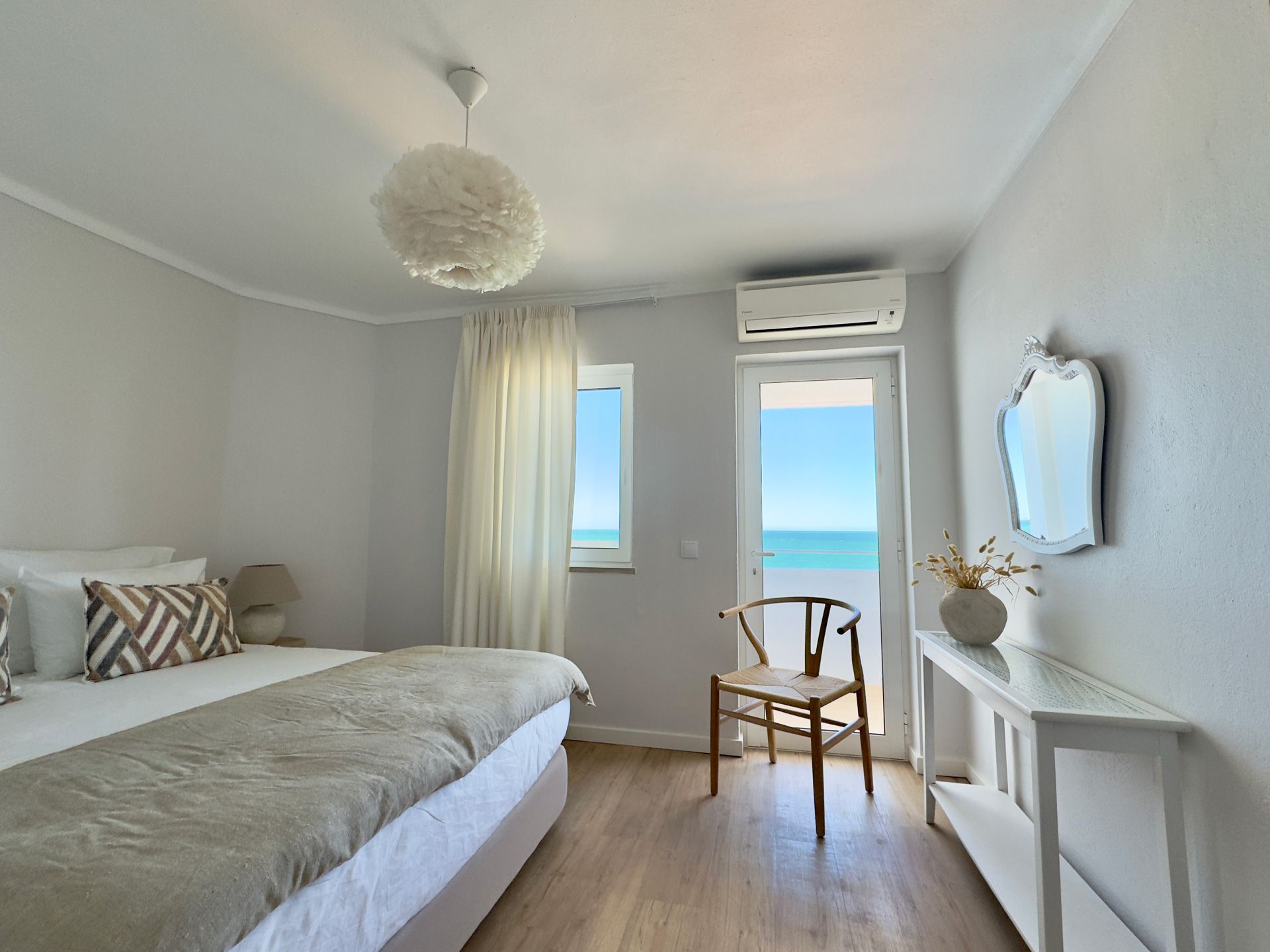 Um quarto com uma cama grande e uma cadeira com vista para o oceano.