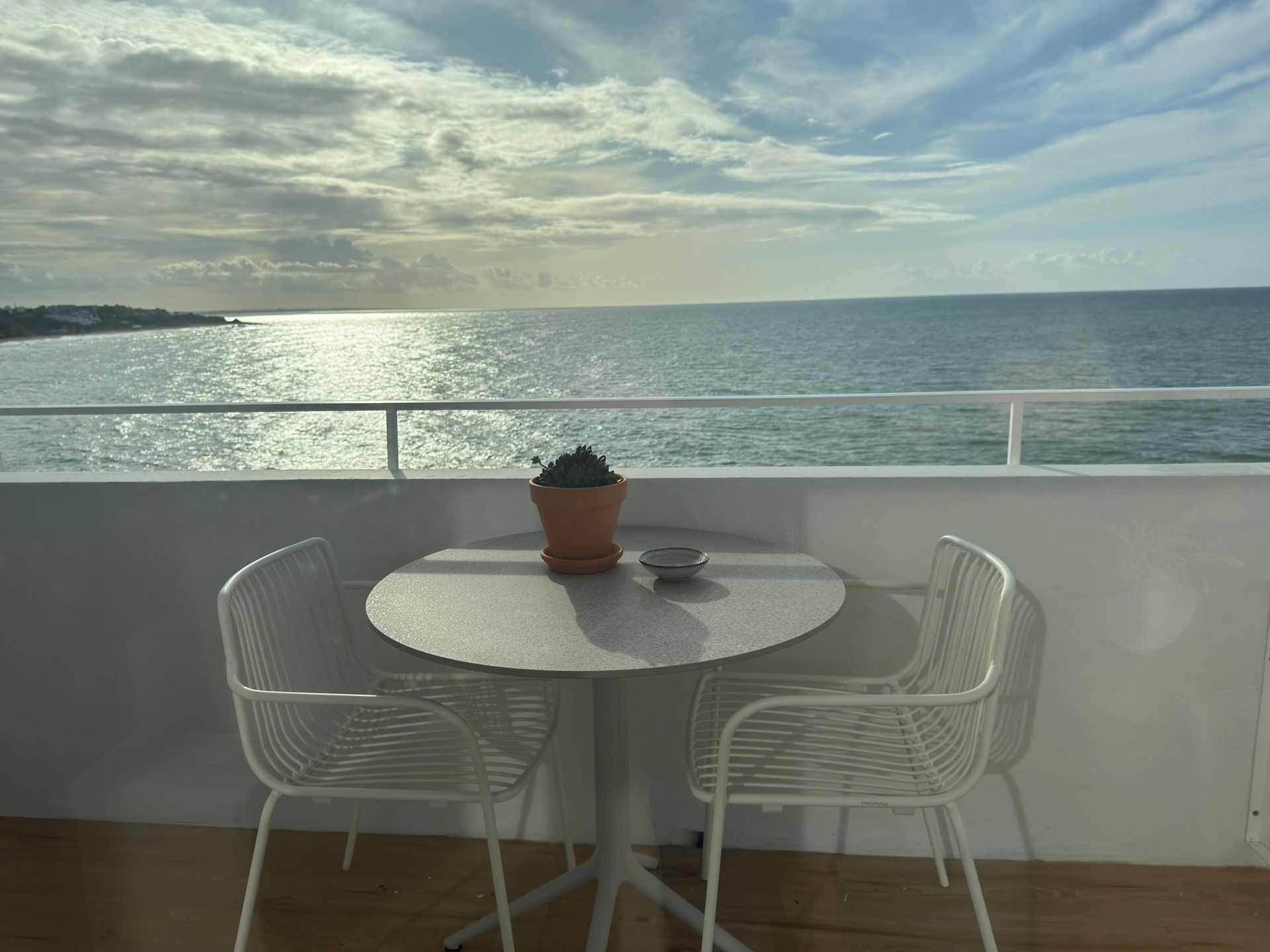 Uma mesa e cadeiras em uma varanda com vista para o oceano.