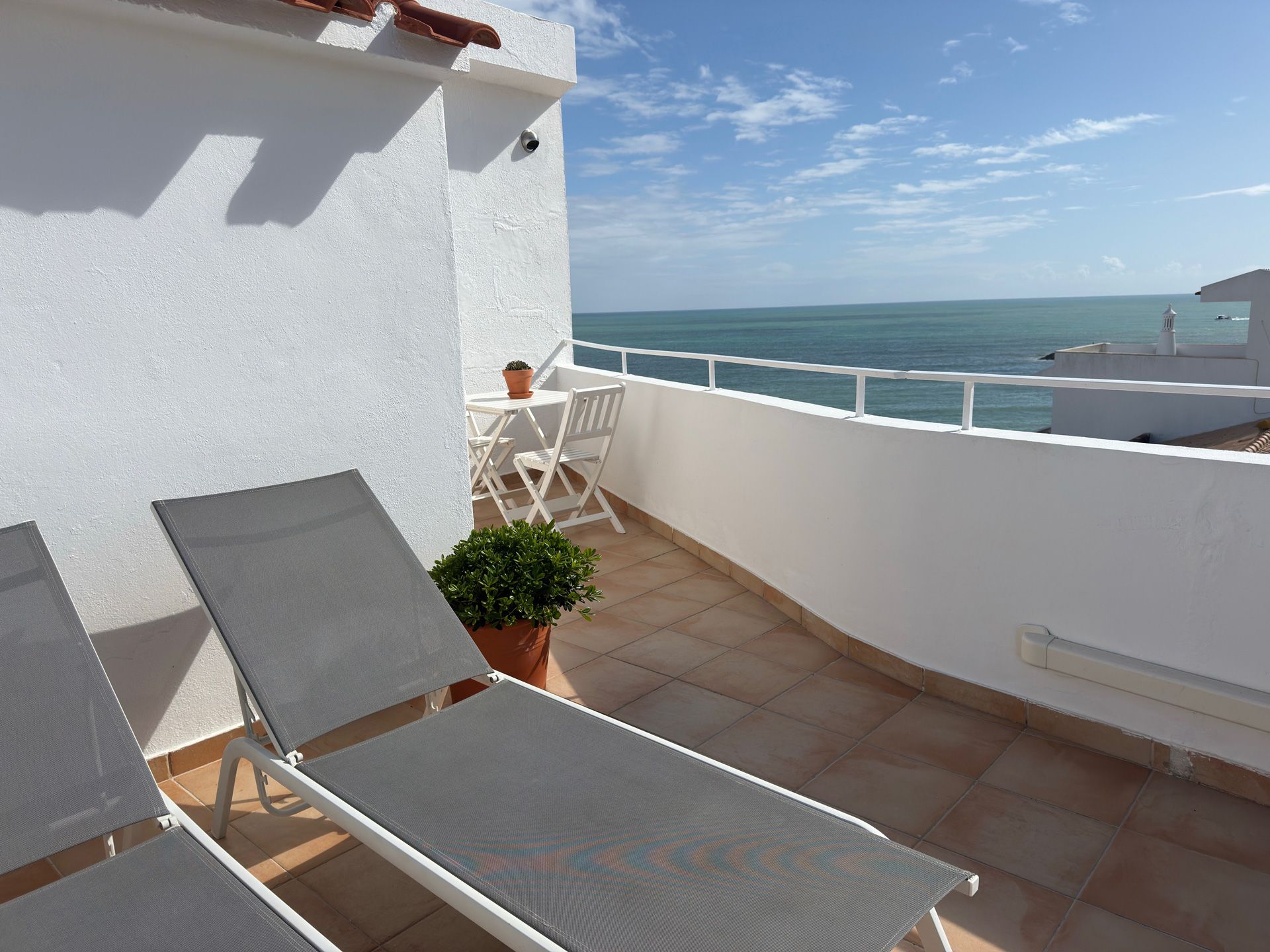 Uma varanda com cadeiras e uma mesa com vista para o oceano