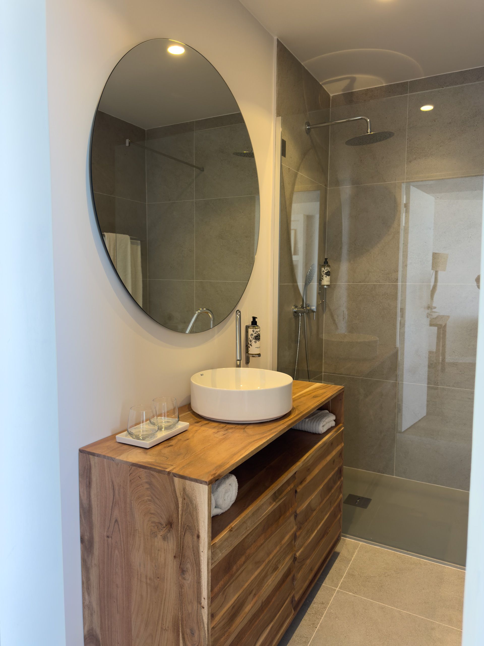 Um banheiro com uma pia e um espelho redondo