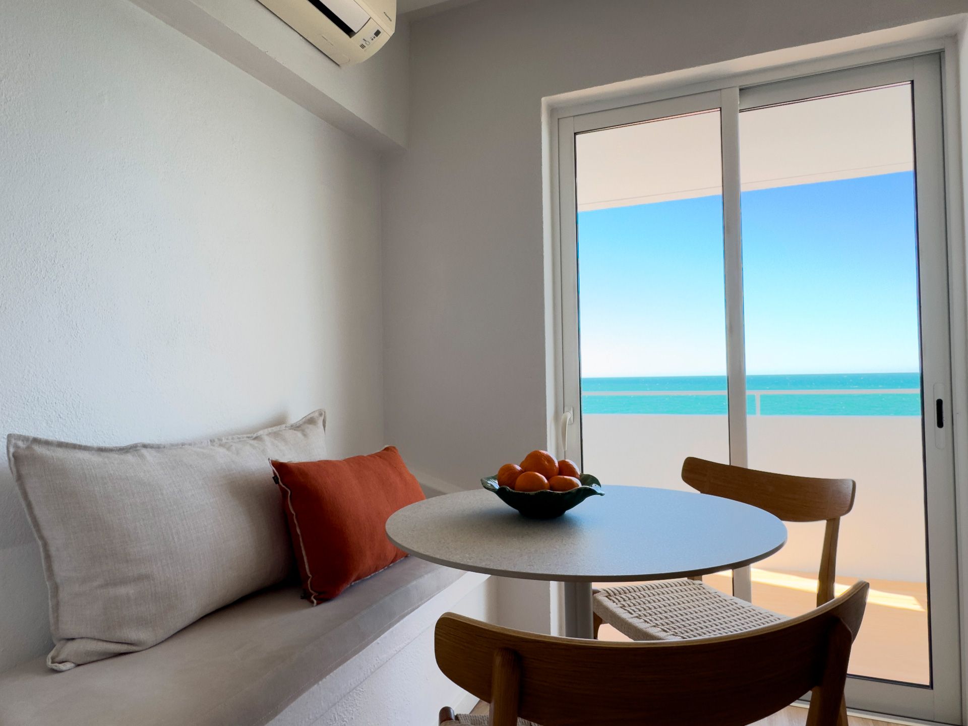 Uma sala de estar com mesa e cadeiras e vista para o oceano