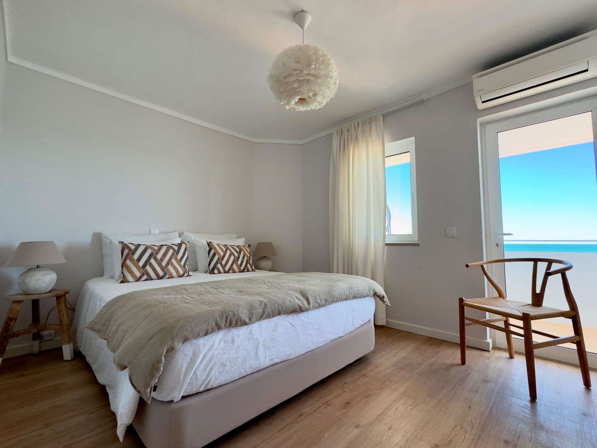 Um quarto com uma cama grande e uma cadeira com vista para o oceano.