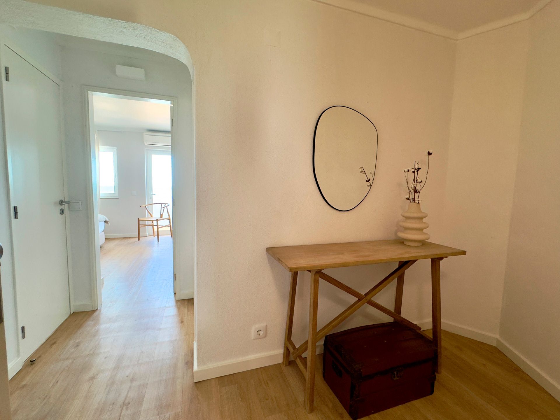 Um corredor com uma mesa de madeira e um espelho na parede.