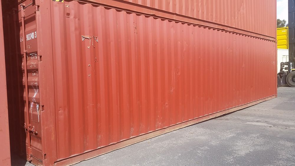 A Large Red Shipping Container Is Sitting On The Ground In A Parking Lot — Oz Shipping Containers in