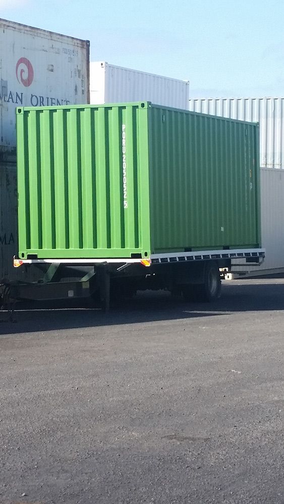 A Green Shipping Container Is Sitting On The Back Of A Truck — Oz Shipping Containers in Teralba, NSW