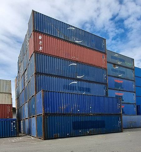 A Stack Of Shipping Containers Are Stacked On Top Of Each Other In A Parking Lot — Oz Shipping Containers in Teralba, NSW
