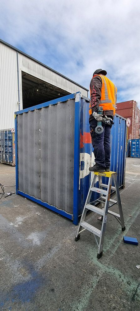 A Man Is Standing On A Ladder Next To A Shipping Container — Oz Shipping Containers in Teralba, NSW