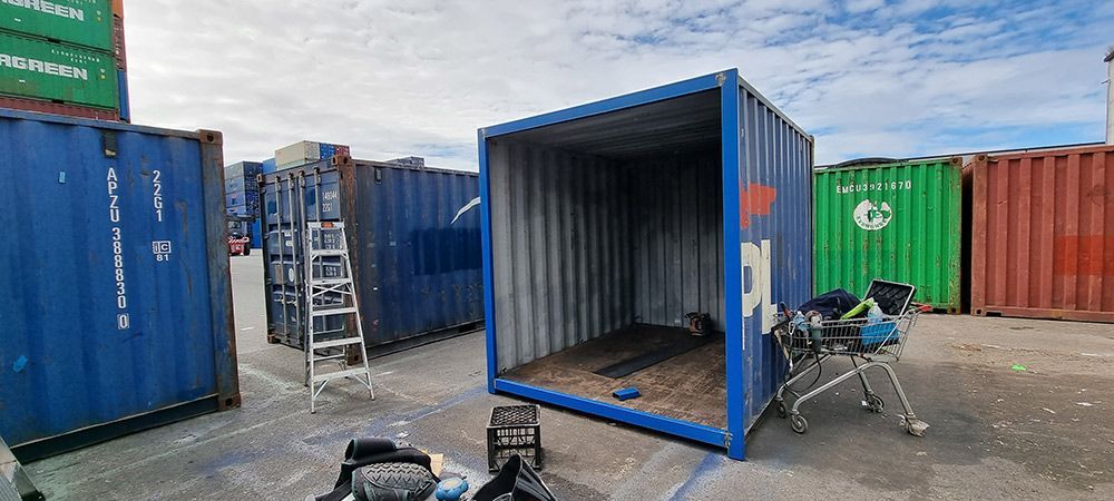 A Blue Shipping Container Is Sitting In A Parking Lot Next To A Chair — Oz Shipping Containers in Teralba, NSW