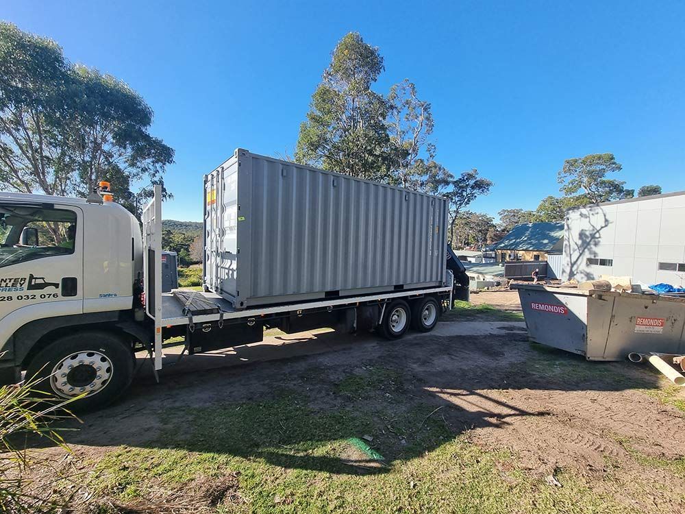 A Truck Is Carrying A Shipping Container On The Back Of It — Oz Shipping Containers in Grafton, NSW