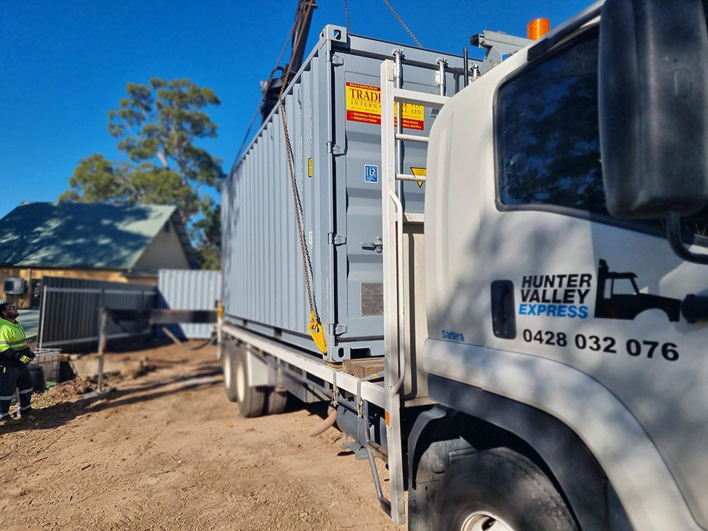 A Hunter Valley Express Truck Is Carrying A Shipping Container — Oz Shipping Containers in Teralba, NSW