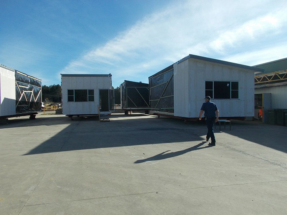 A Man Is Walking In Front Of A Row Of Buildings — Oz Shipping Containers in Teralba, NSW