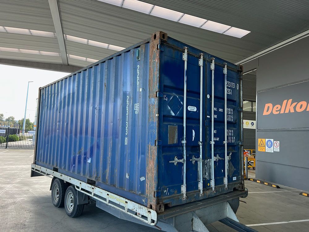 A Blue Shipping Container Is Being Towed By A Trailer — Oz Shipping Containers in Teralba, NSW