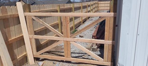 A wooden gate is being built next to a wooden fence.