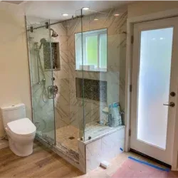 Modern bathroom with glass shower, toilet, and frosted glass door.