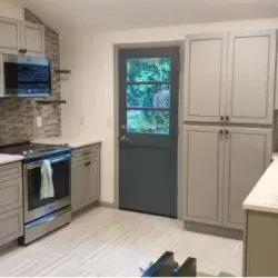 Kitchen with gray cabinets, stainless steel appliances, and a dark blue door leading outside.