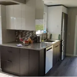 Modern kitchen with white and dark gray cabinets, stainless steel appliances, and a mosaic backsplash.