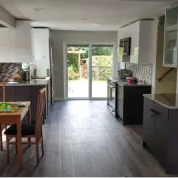 Modern kitchen with gray cabinets, wood flooring, and a glass door leading to a deck.