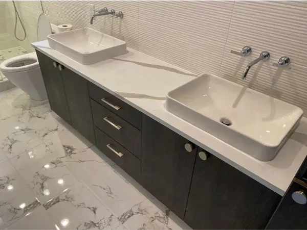 Bathroom with dark wood vanity, white countertop, two vessel sinks, and wall-mounted faucets.