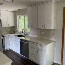 White kitchen with cabinets, stainless steel appliances, and a window.