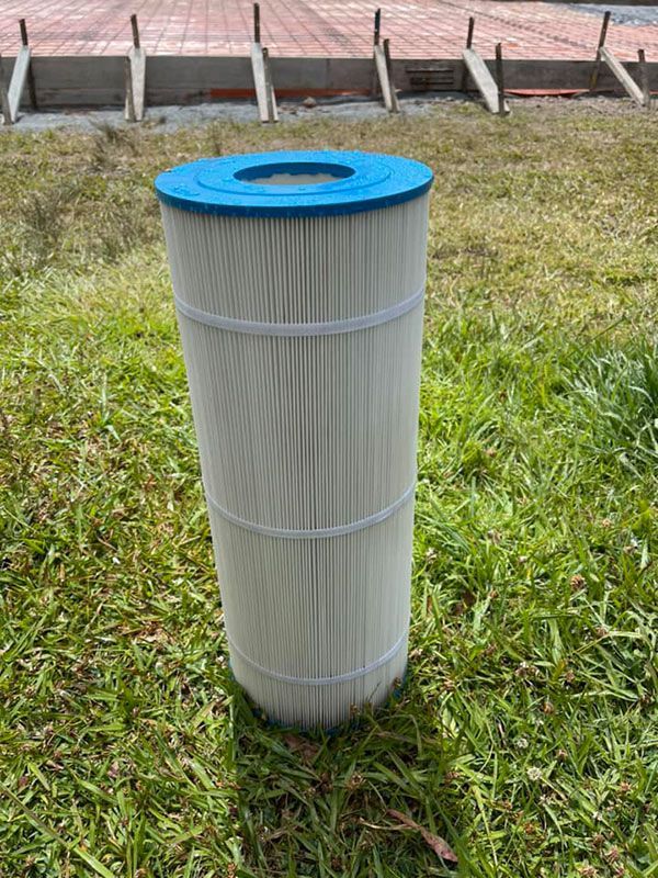 A Pool Filter is Sitting on Top of a Lush Green Field — Taree Pool Supplies in Harrington, NSW