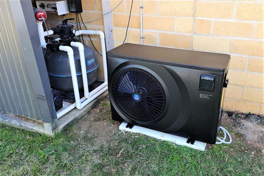 A Swimming Pool Heater is Sitting Next to a Brick Wall — Taree Pool Supplies in Wingham, NSW