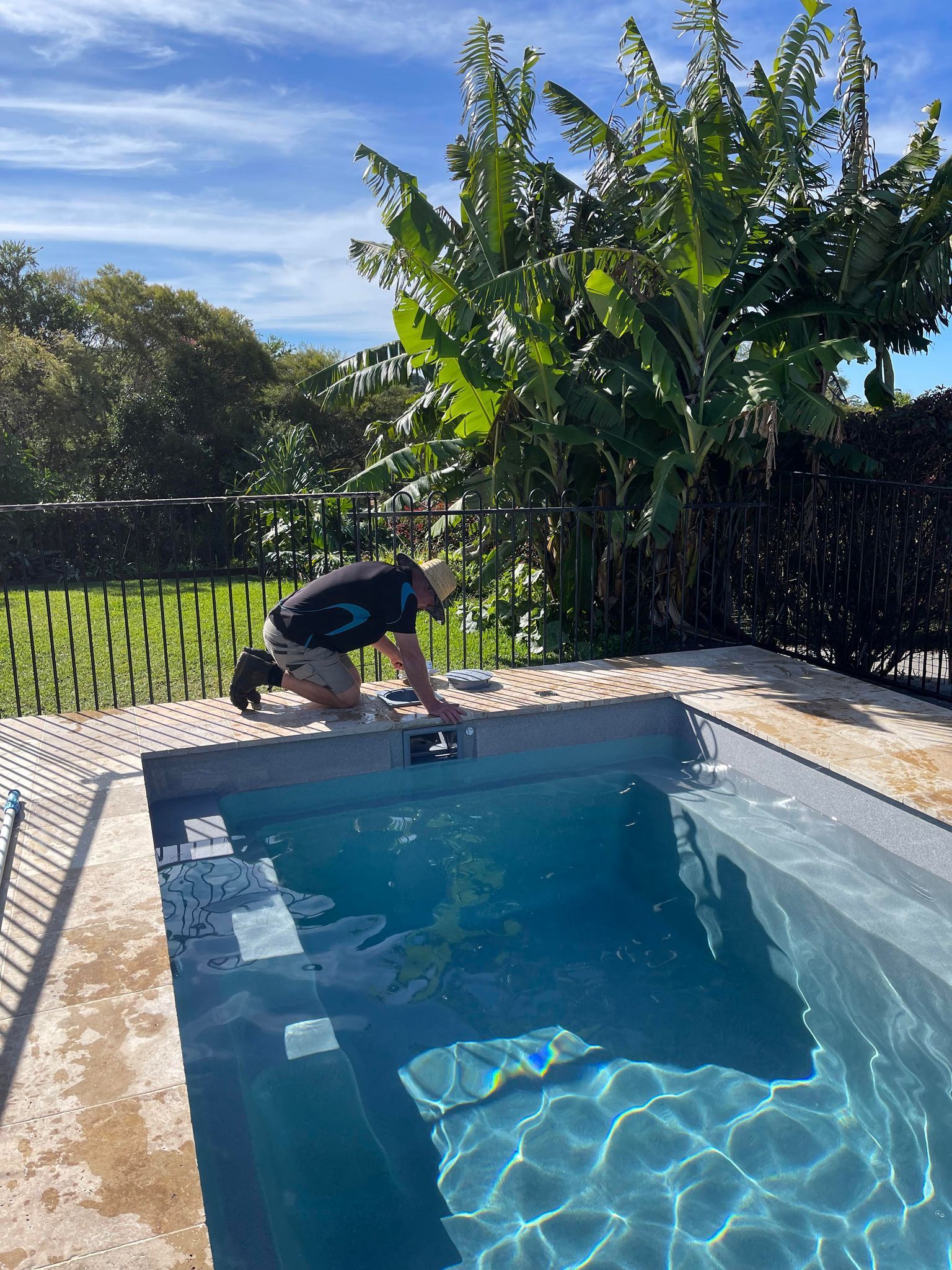 A Man is Kneeling on the Edge of a Swimming Pool — Taree Pool Supplies in Taree, NSW