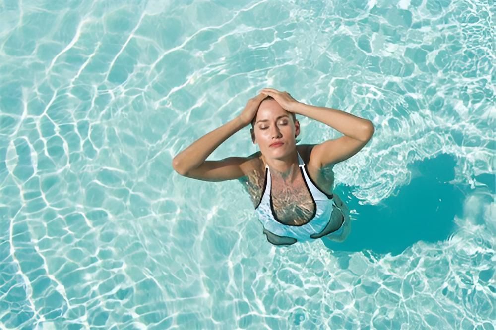 A Woman is Swimming in a Swimming Pool With Her Eyes Closed — Taree Pool Supplies in Taree, NSW