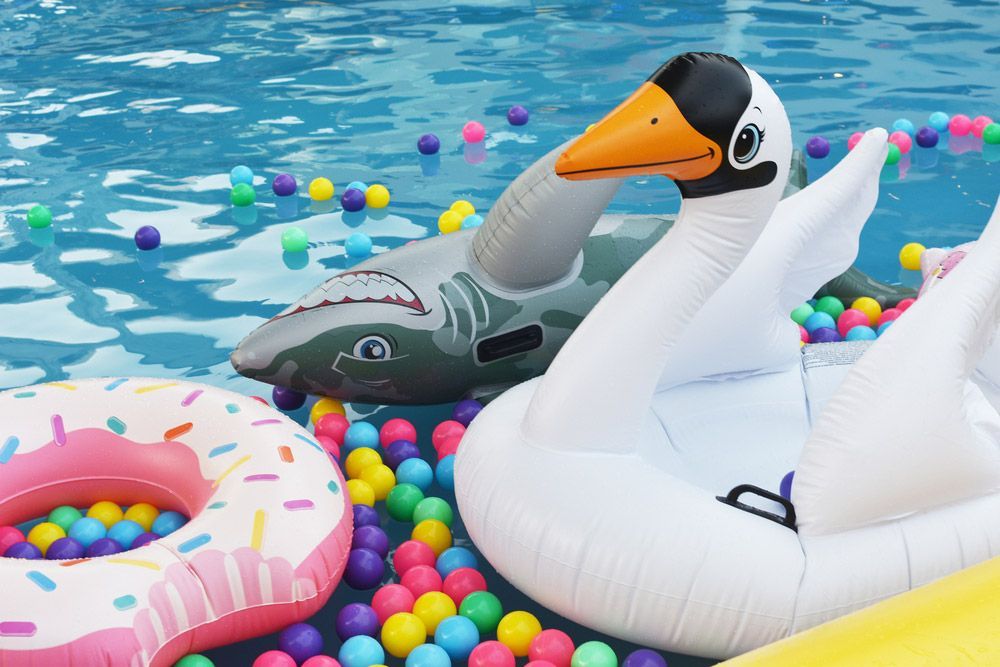 A Swan Float is Floating in a Pool Surrounded by Colourful Balls — Taree Pool Supplies in Harrington, NSW