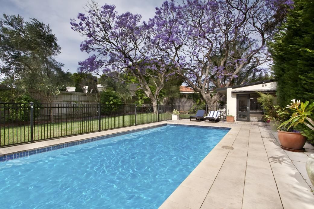 A Large Swimming Pool With Purple Flowers in the Background — Taree Pool Supplies in Forster, NSW