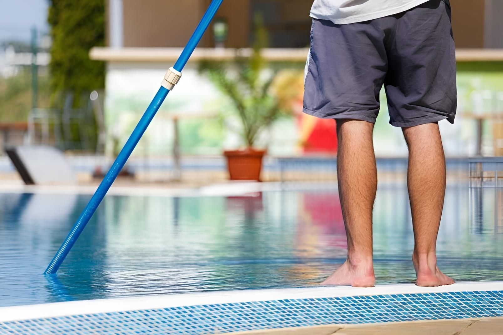A Man is Cleaning a Swimming Pool With a Broom — Taree Pool Supplies in Forster, NSW
