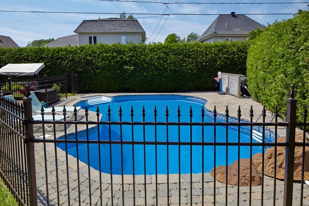 A Fence Surrounds a Large Swimming Pool in a Backyard — Taree Pool Supplies in Hallidays Point, NSW