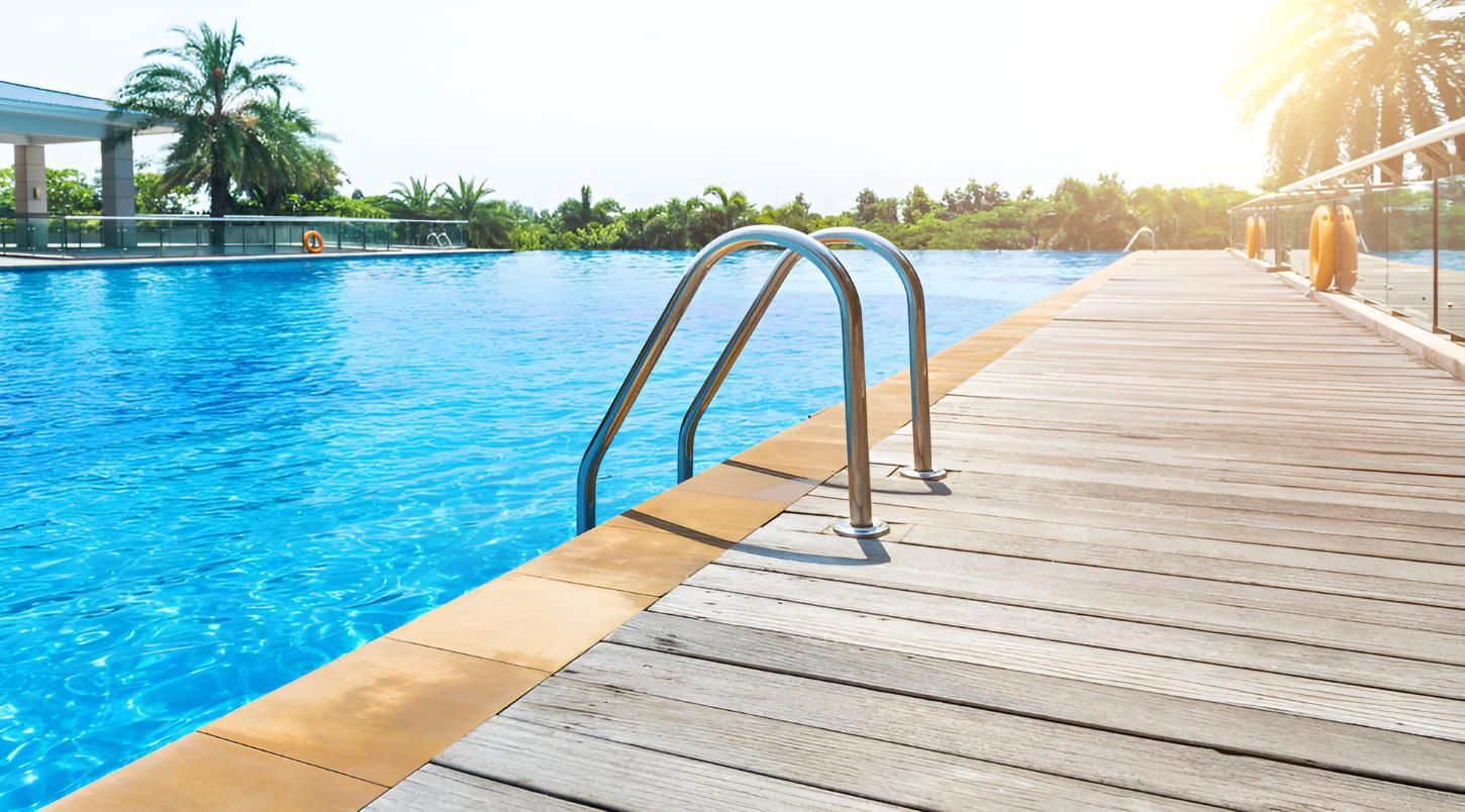 A Swimming Pool With a Wooden Deck and Stairs Leading to It — Taree Pool Supplies in Harrington, NSW