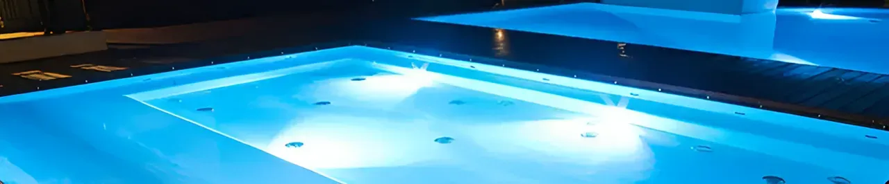 A Large Swimming Pool is Lit Up at Night With Blue Lights — Taree Pool Supplies in Taree, NSW