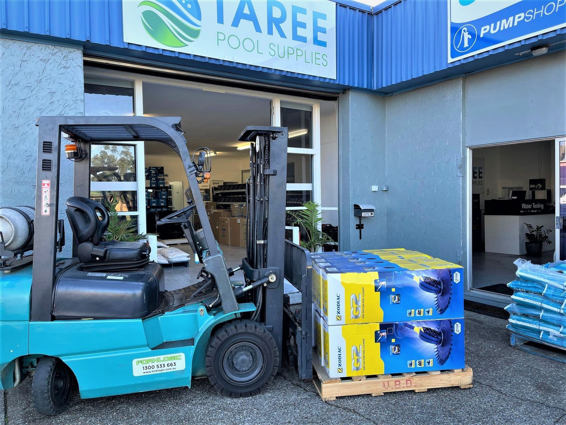 Turquoise Forklift is Lifting a Pallet of Pool Supplies