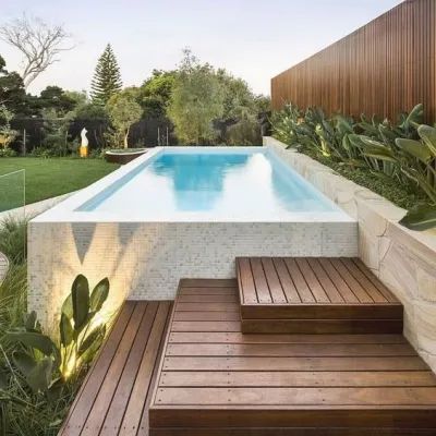 A Swimming Pool is Surrounded by a Wooden Deck and a Wooden Fence — Taree Pool Supplies in Taree, NSW