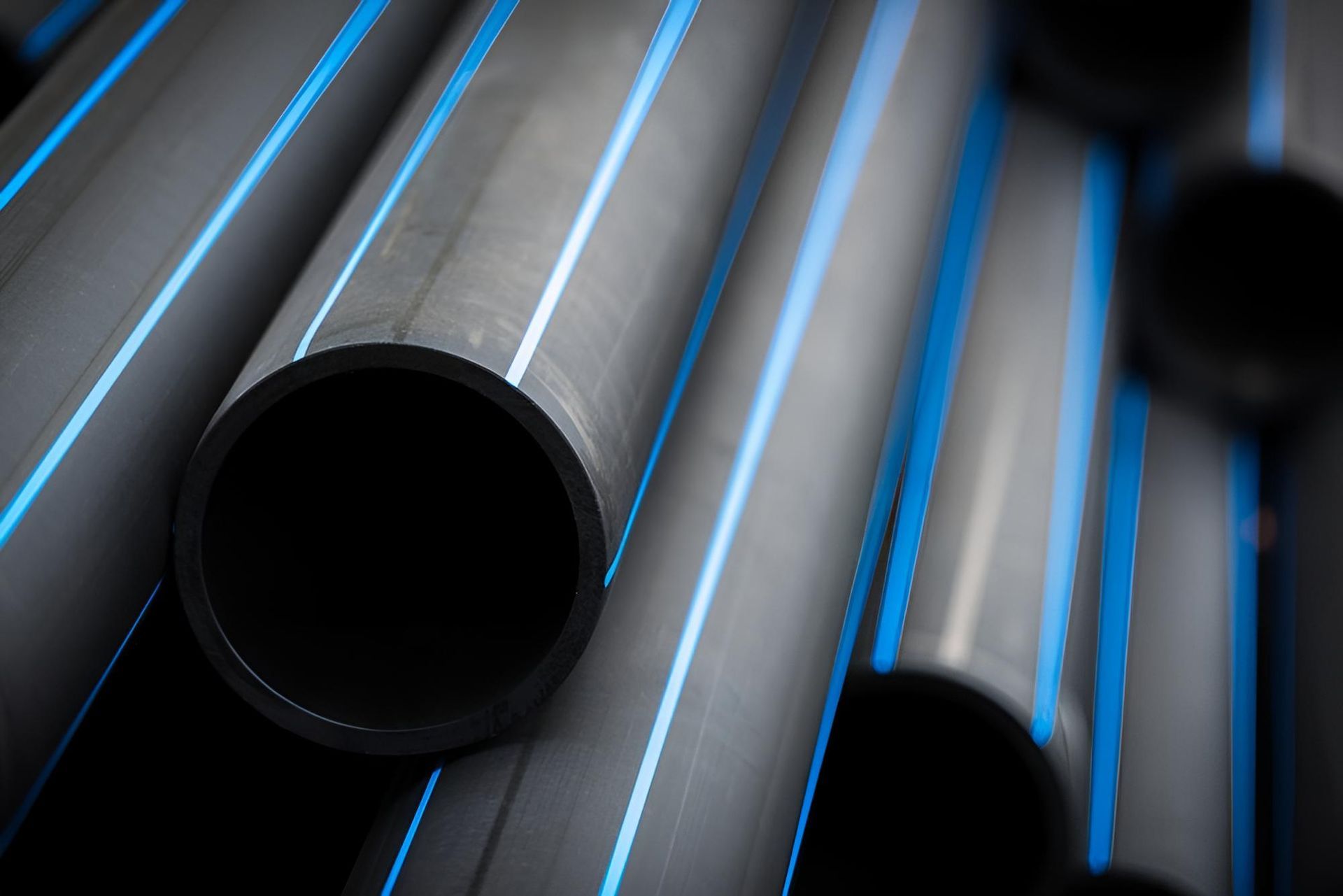 A Bunch of Black Pipes With Blue Stripes on Them Are Stacked on Top of Each Other — Taree Pool Supplies in Forster, NSW