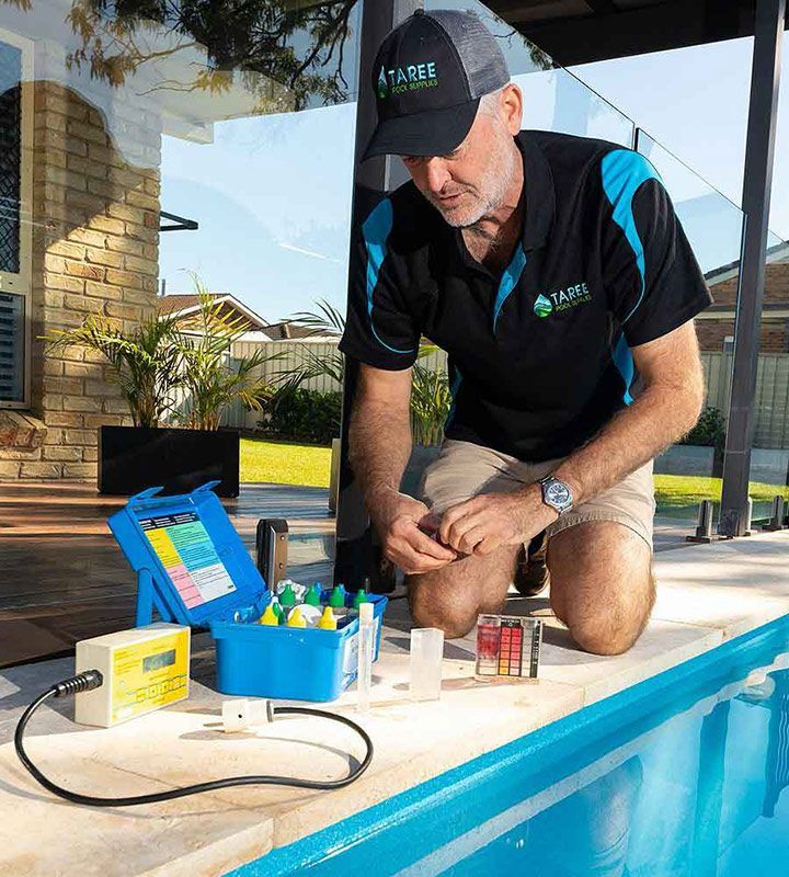 A Man is Kneeling on the Edge of a Swimming Pool — Taree Pool Supplies in Taree, NSW