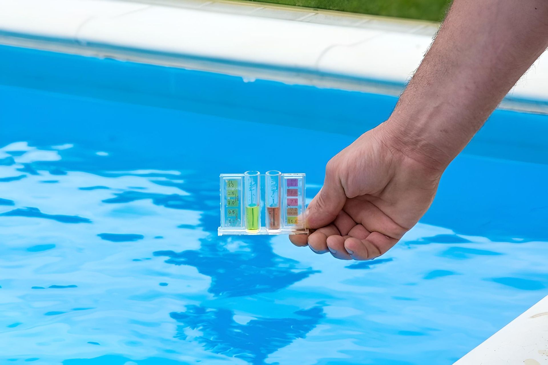 A Person is Holding a Test Kit in Front of a Swimming Pool — Taree Pool Supplies in Forster, NSW