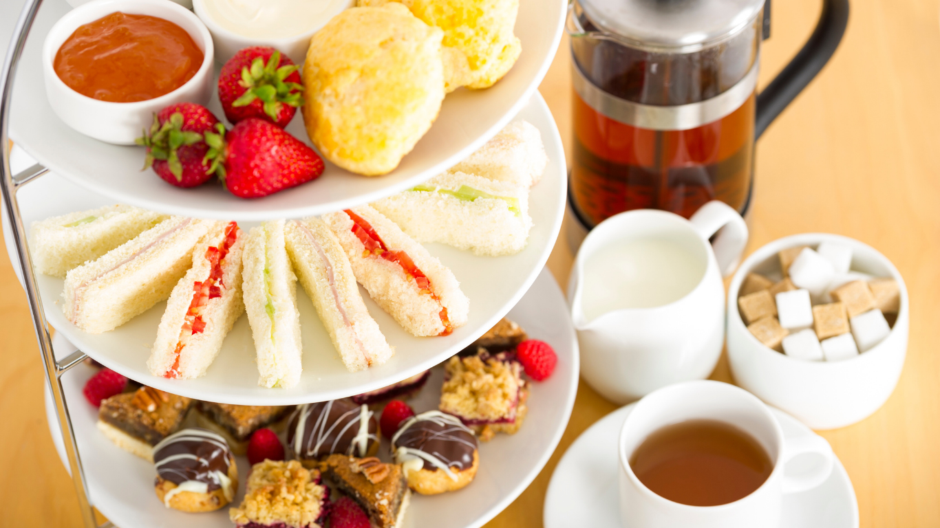 Woman with windblown brown hair laughs, wearing a green shirt.