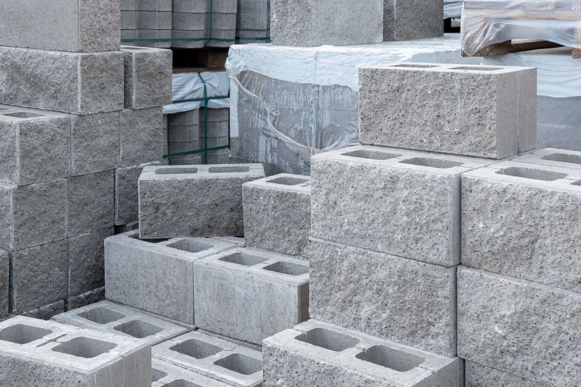 A stack of gray concrete masonry units, also known as cinder blocks, stored on pallets.