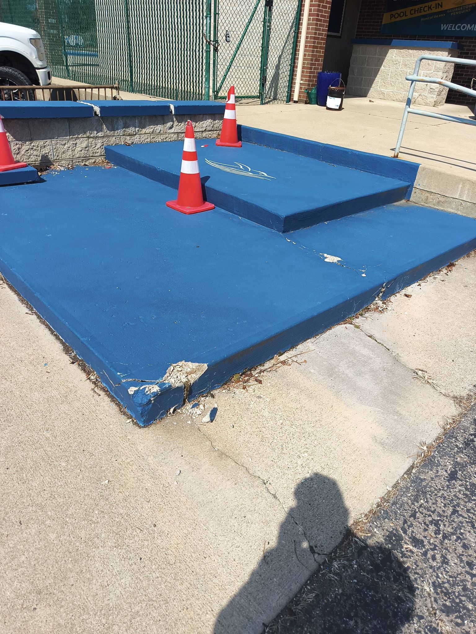 A person in a high-visibility vest spreads mortar with a trowel while building a block wall.