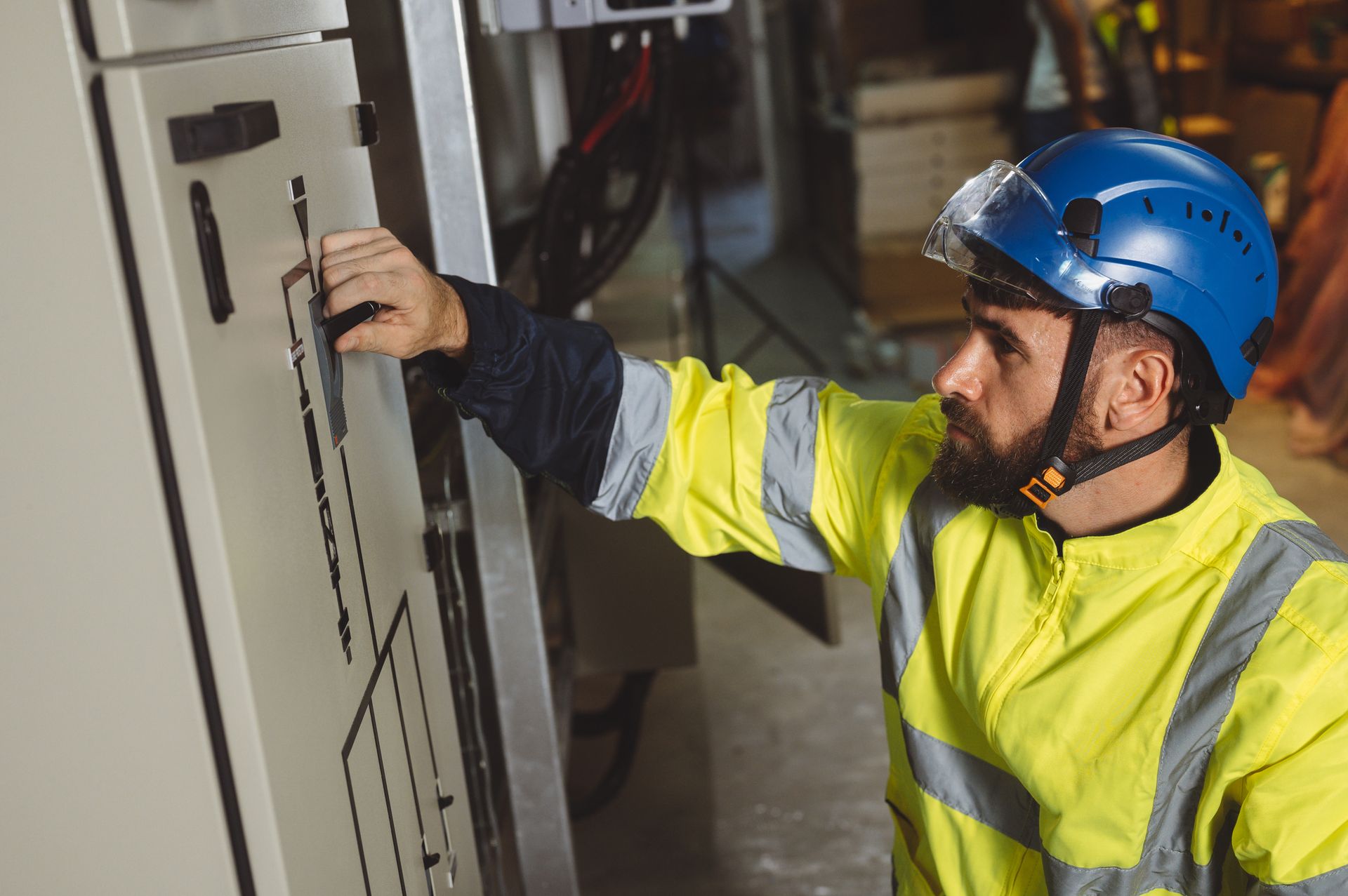 A man wearing a helmet and safety vest is working on a machine.