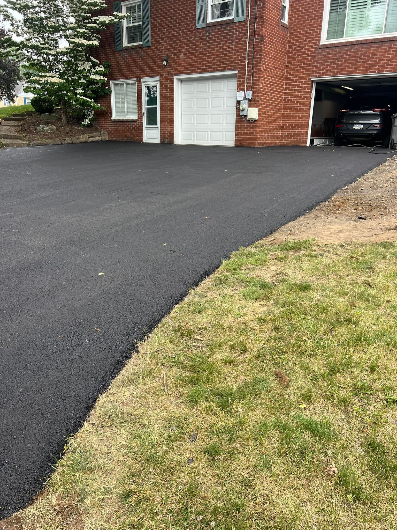 A car is parked in a garage next to a brick house.